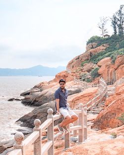 Man standing on rock against sky