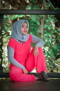 Portrait of young woman sitting on railing