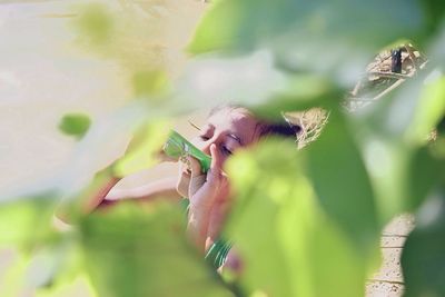 Child outdoors behind leaves in a sunny day