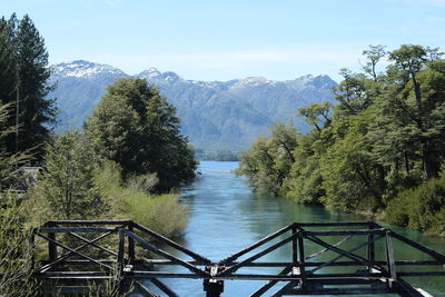 Scenic view of river by mountains against sky