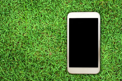High angle view of mobile phone in grass