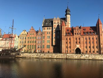 Low angle view of buildings by canal against clear sky