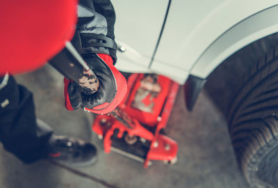 Low section of mechanic using hydraulic jack in garage