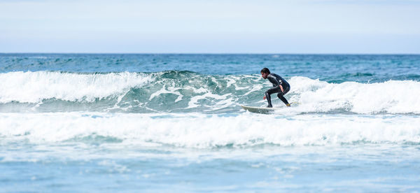 Man surfing in sea against sky