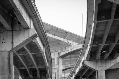 Low angle view of elevated road amidst buildings against sky