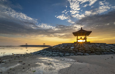 Lifeguard hut on beach against sky during sunset