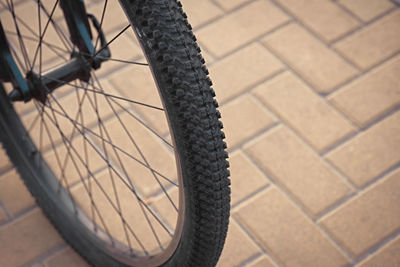 Bicycle front wheel outdoors on tiled road close up