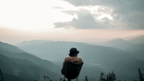 Rear view of man looking at landscape during sunset