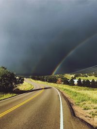 Rainbow over road against sky