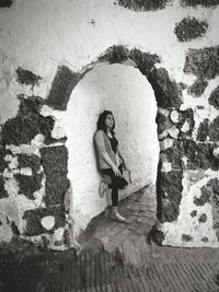 Woman looking away while standing against wall