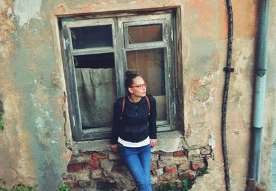 High angle view of woman leaning against abandoned window