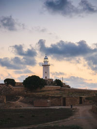 Lighthouse on landscape against cloudy sky