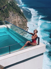 Woman sitting by swimming pool