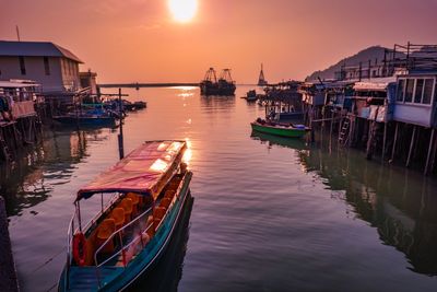 Boats moored in canal against sky during sunset