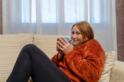 Portrait of a smiling young woman sitting on sofa