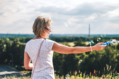 Rear view of woman blowing bubbles outdoors