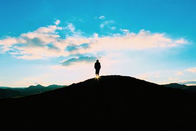 Silhouette person standing on hill against sky