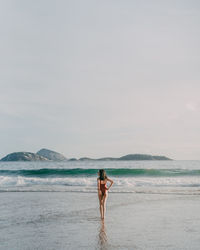 Woman standing at beach against sky