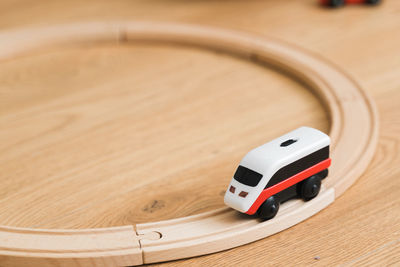 Toddler girl in white dress plays with wooden train at home in the living room