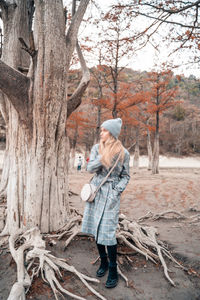 Side view of woman standing on tree trunk