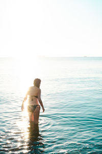 Full length of shirtless man in sea against sky