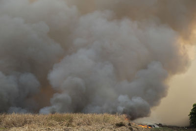 Smoke emitting from chimney on land against sky