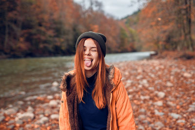 Portrait of smiling young woman standing during autumn