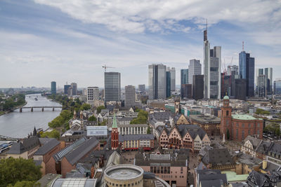 Aerial view of buildings in city against cloudy sky