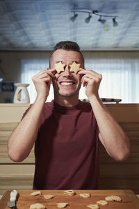 Funny portrait of young man during baking christmas sweets at home kitchen.