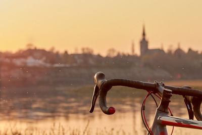 Part of a black red gray racing bike on the river in the yellow orange evening near the city dresden