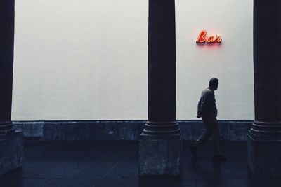 Man walking on sidewalk by bar