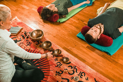 Therapist playing rin gong by couple while performing music therapy at spa