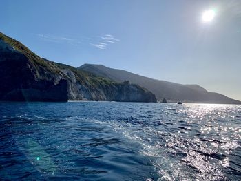 Scenic view of sea and mountains against blue sky