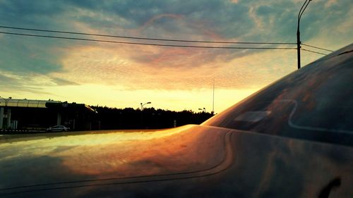 Power lines against cloudy sky at sunset