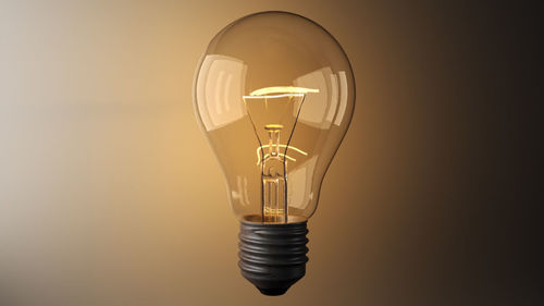 Close-up of illuminated light bulb levitating against wall