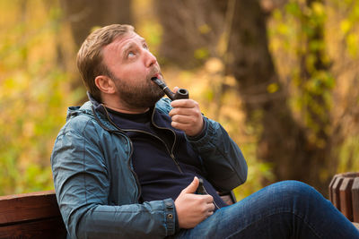 Man smoking pipe while sitting on bench