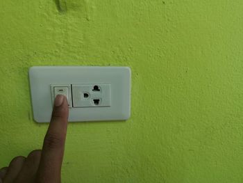 Close-up of human hand on green wall