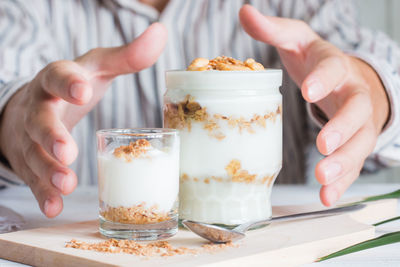 Midsection of woman holding ice cream in glass on table