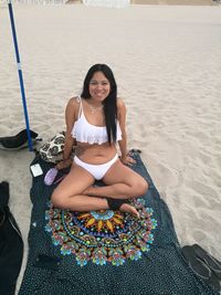 Portrait of woman wearing bikini while sitting at beach