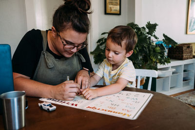 Mom and young son painting finger nails at kitchen table