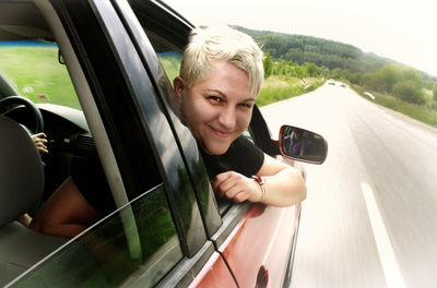 Portrait of smiling woman peeking through car window