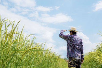 Man standing amidst plants on land against sky