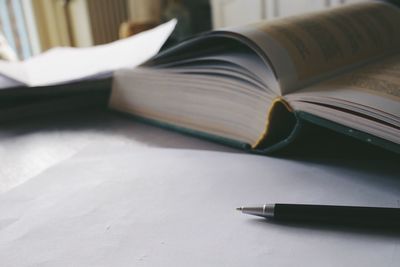 Close-up of open book pen on table