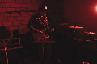 Group of musicians playing in red neon lights at music studio