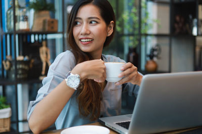 Young woman drinking coffee while sitting in cafe