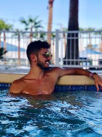 Young man in swimming pool against sky