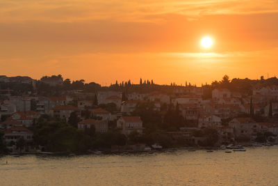 Scenic view of sea by buildings against sky during sunset