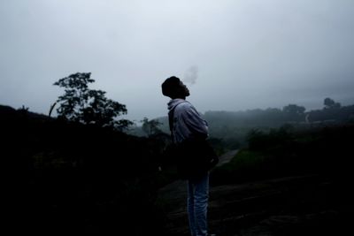 Rear view of man standing on field against sky