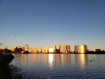 Buildings by river against clear sky