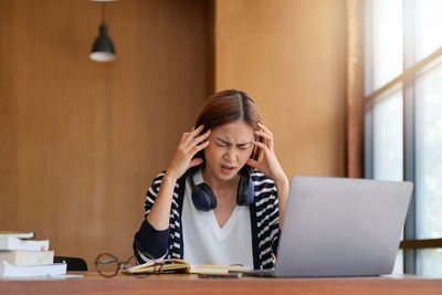 Young woman using mobile phone while sitting on table